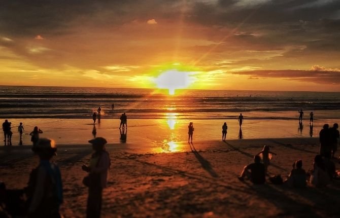 Golden sunset on Kuta Beach with silhouettes of people on the sand
